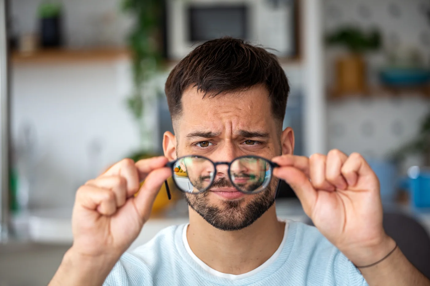 Crop anonymous female optometrist wearing medical robe holding modern trial frame with lenses in hands in modern optometry clinic